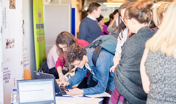 Students using a laptop at a busy recruitment fair, ҹɫֱ campus, Edinburgh