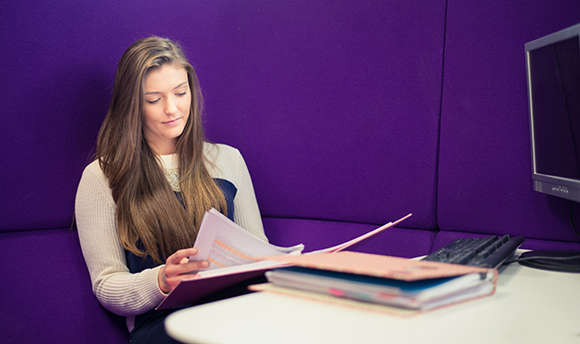 A ҹɫֱ student reading over their work against a purple wall