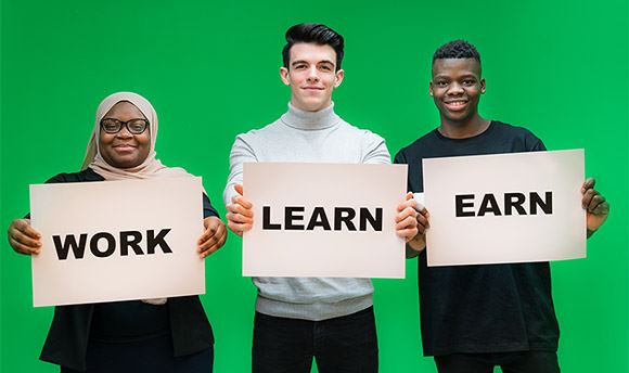 Three ҹɫֱ students holding signs with the words "Work", "Learn" and "Earn"