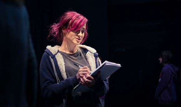 A ҹɫֱ stage management student reading and making notes on a notepad on stage