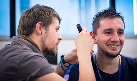ҹɫֱ Hearing Aid Audiology student using a piece of equipment to test another student's hearing