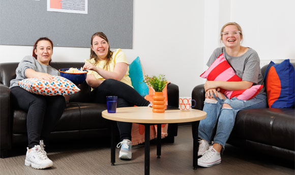 Three female students enjoy popcorn while watching a film in their ҹɫֱ Student Accommodation